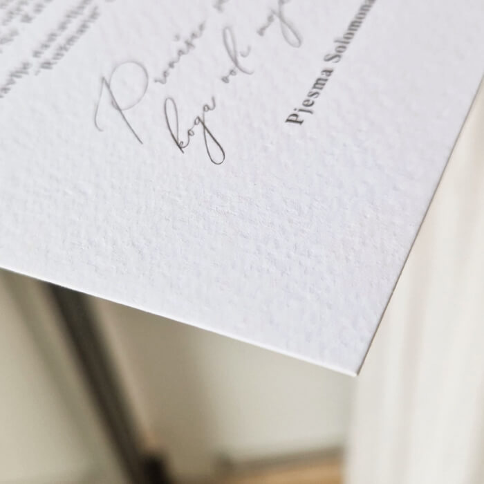 Detaljni prikaz premium pozivnice za vjenčanje s elegantnim rukopisnim tipografijom na teksturiranom papiru.