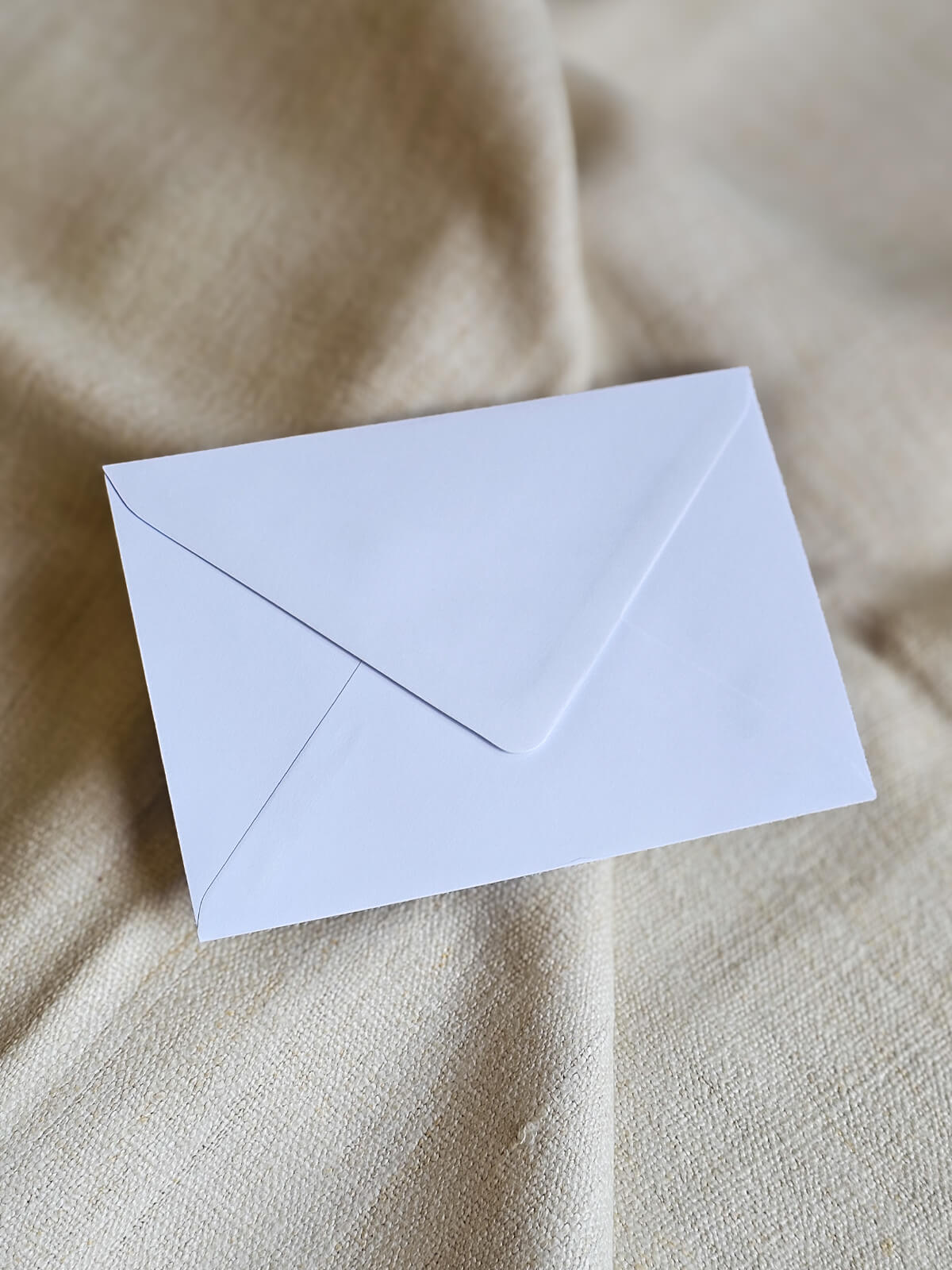 Bijela kuverta za pozivnicu za vjenčanje na mekoj bež pozadini, jednostavan i elegantan dizajn