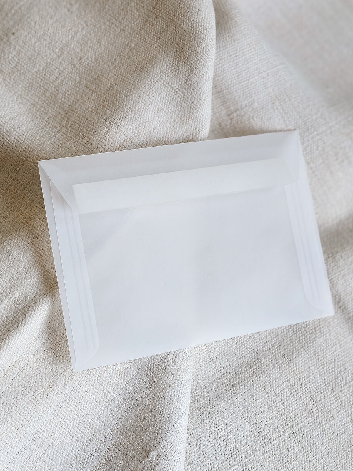 Jednostavna bijela kuverta na tkanini bež boje, idealna za elegantne pozivnice za vjenčanje