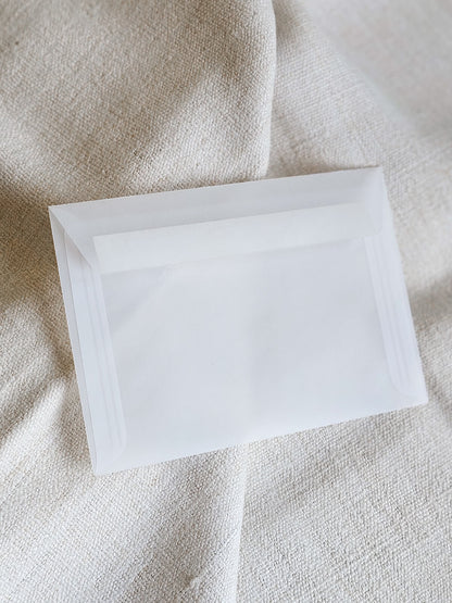 Jednostavna bijela kuverta na tkanini bež boje, idealna za elegantne pozivnice za vjenčanje