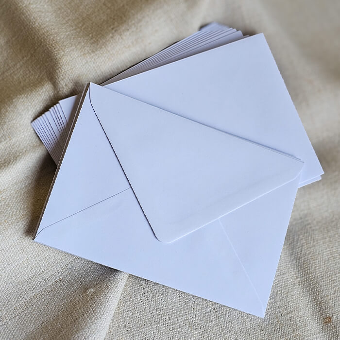 Stog bijelih kuverti za pozivnice za vjenčanje, pripremljen za slanje s ljubavlju