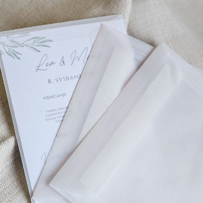 Prozirne kuverte za vjenčane pozivnice, elegantno složene na mekoj tkanini