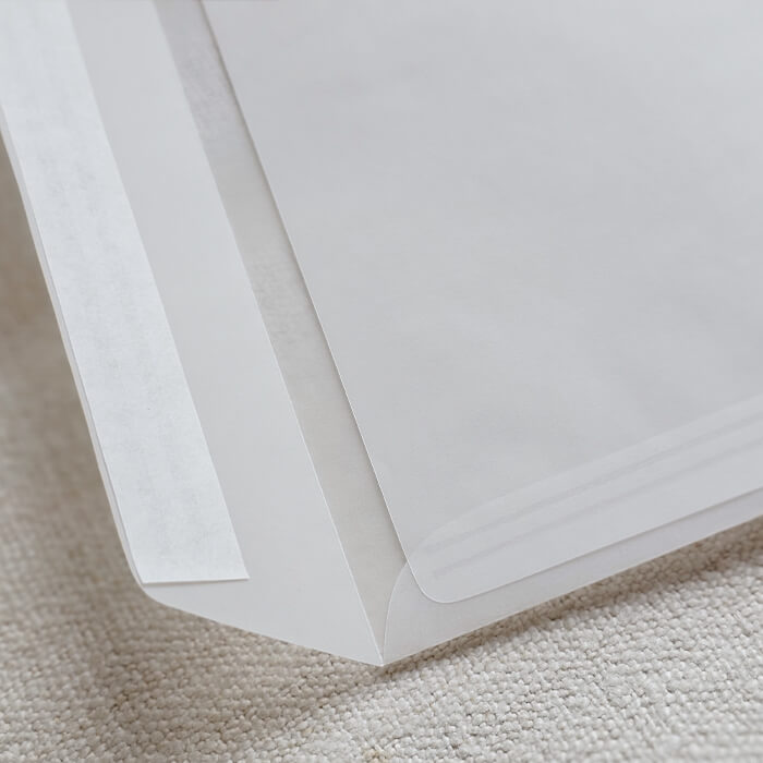 Detaljni prikaz bijele kuverte s prozirnim trakama, savršeno za sofisticirane vjenčane pozivnice