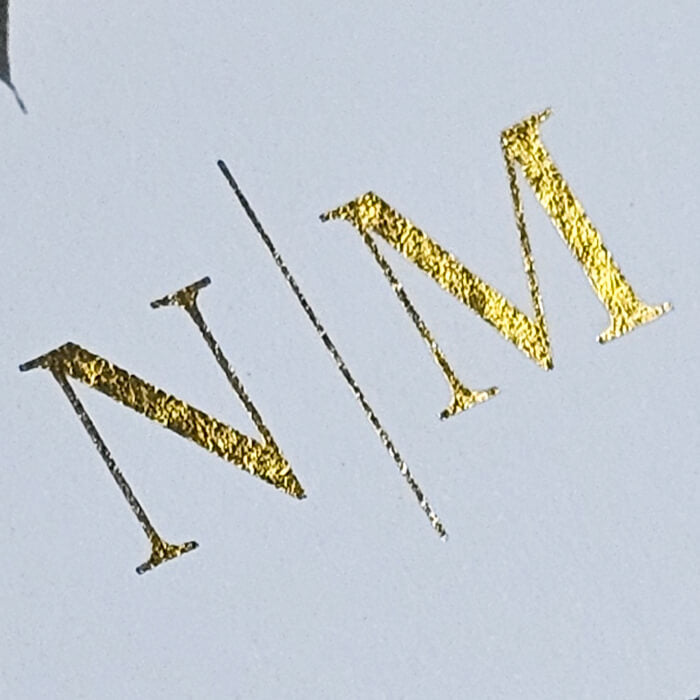 Detalj zlatnih inicijala na vjenčanoj pozivnici s eukaliptusom, sofisticirani detalji tiska